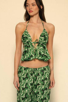 Woman wearing green and cream floral halter tank top with matching patterned skirt against beige background.