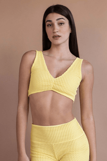Yellow crochet bikini top with V-neckline and textured knit fabric, displayed on model against neutral background.