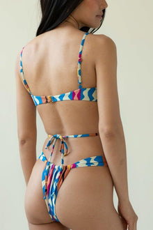 Bikini bottom with colorful abstract striped pattern in blue, pink, yellow, and cream, featuring tie-side fastening.