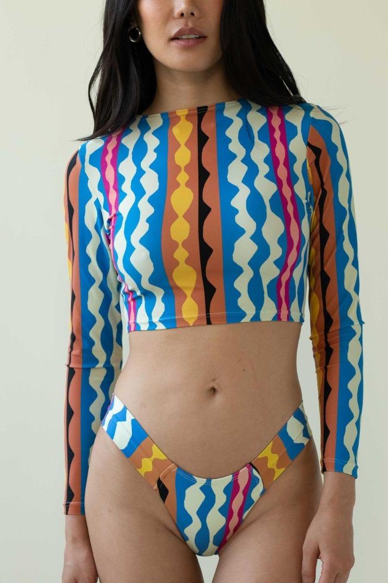 Bikini bottom with blue, yellow, pink, and orange abstract geometric wave pattern on cream background.