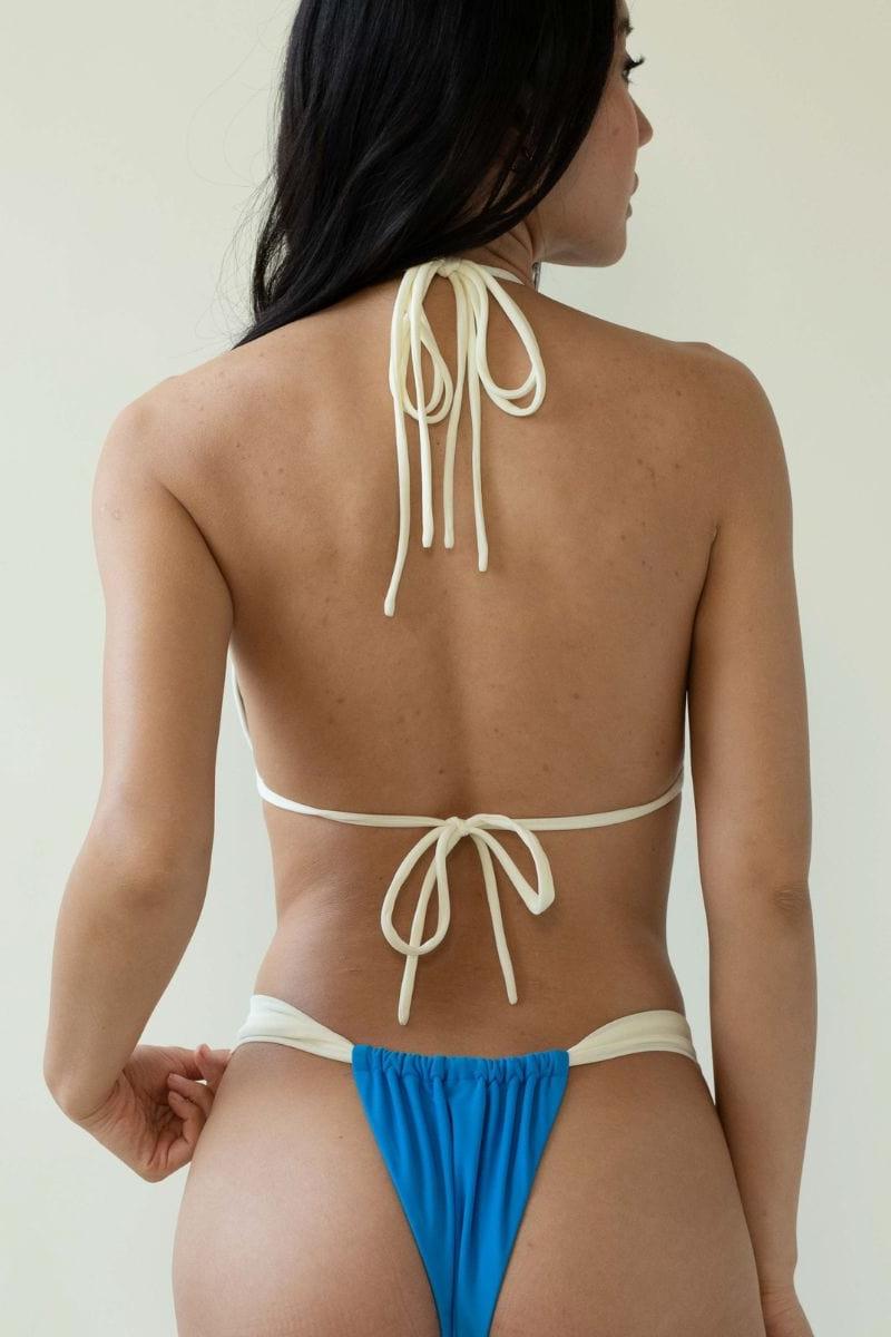 Cream and blue bikini bottom with gathered blue fabric panel and cream binding at waistband, shown from back view.
