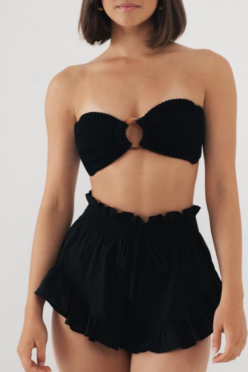 Black strapless bikini top with center ring detail and matching ruffled shorts.