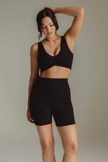 Black ribbed bikini top with V-neckline and crossover front design on model.