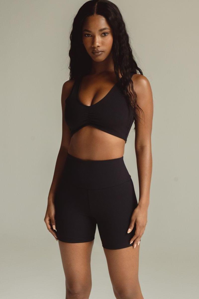 Black ribbed bikini top with V-neckline and sleeveless design on model.