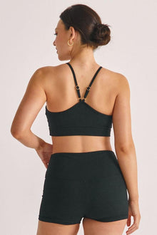 Black ribbed micro shorts with high waistband, shown from back view on model wearing matching sports bra.