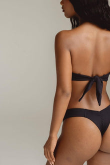 Black ribbed bikini bottom with tie-back closure, shown from rear view on model.