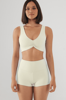 Cream ribbed bikini top with V-neckline and ruched center detail on model.