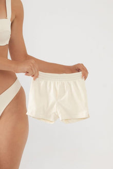 Cream ribbed swim trunks with elastic waistband, displayed on model.