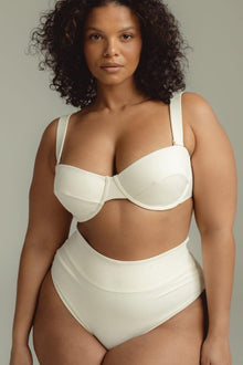 Cream ribbed bustier bikini top with underwire cups and adjustable shoulder straps on model.