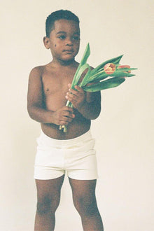 Child wearing cream ribbed swim trunks with drawstring waist.