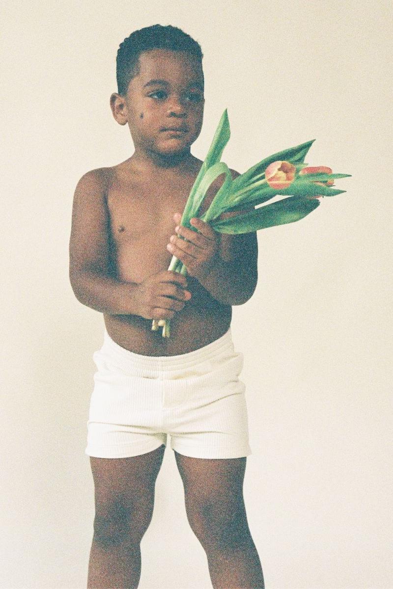 Child wearing cream ribbed swim trunks with drawstring waist.