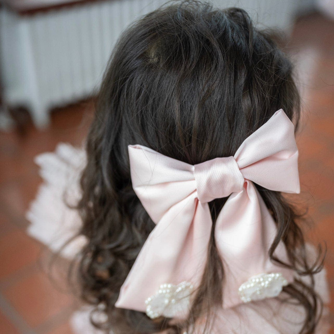Girl wearing large pink satin bow with flower embellishments