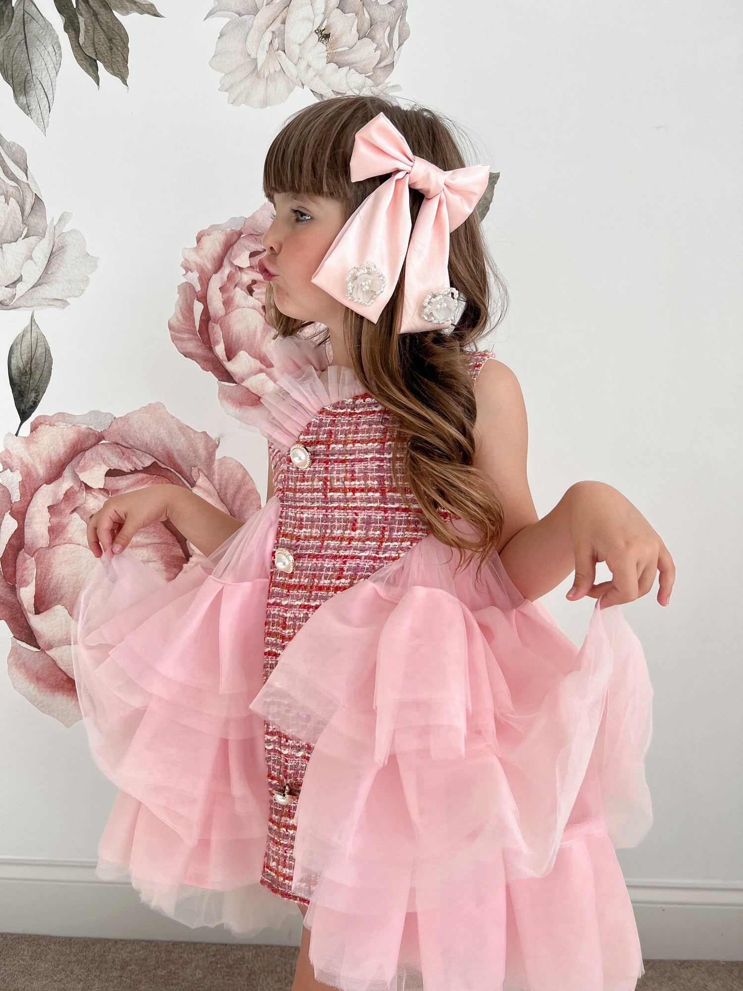 Girl wearing large clip on pink satin bow with flower embellishments