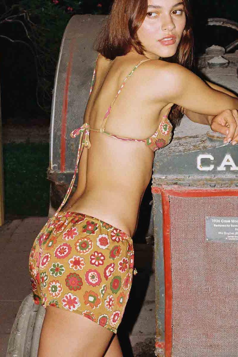 Gold silk shorts with red, pink, and green floral print and drawstring waistband.