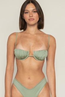 Sage green bikini top with ruched petal cups, thin straps, and center cutout detail on model.