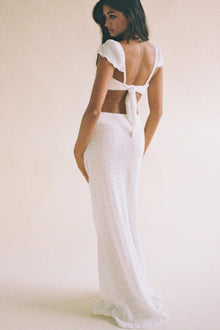 White ribbed maxi skirt with high waist and side slit, worn with matching tie-back crop top.