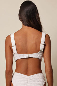 White textured bikini top with square neckline, adjustable shoulder straps, and hook-and-eye back closure, shown from rear vi