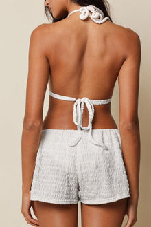 White textured low-rise drawstring shorts with white rope ties at back waist.