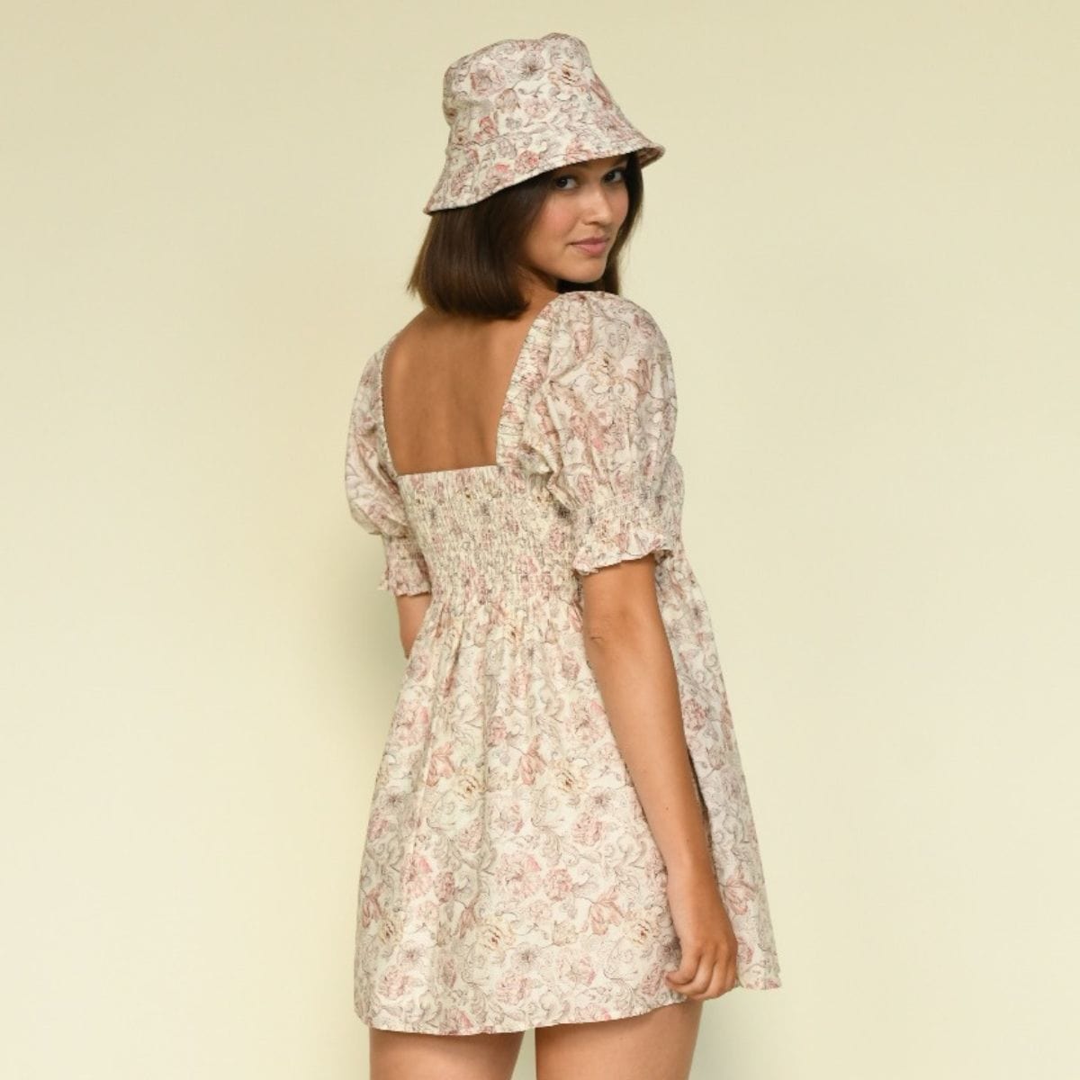 Cream bucket hat with pink floral pattern, shown worn with matching floral dress.