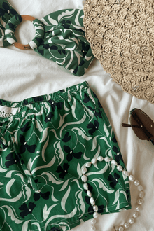 Green and cream floral print shorts with drawstring waist and elastic leg openings.