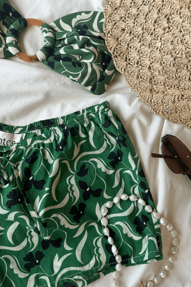 Green and cream floral print shorts with drawstring waist and elastic leg openings.