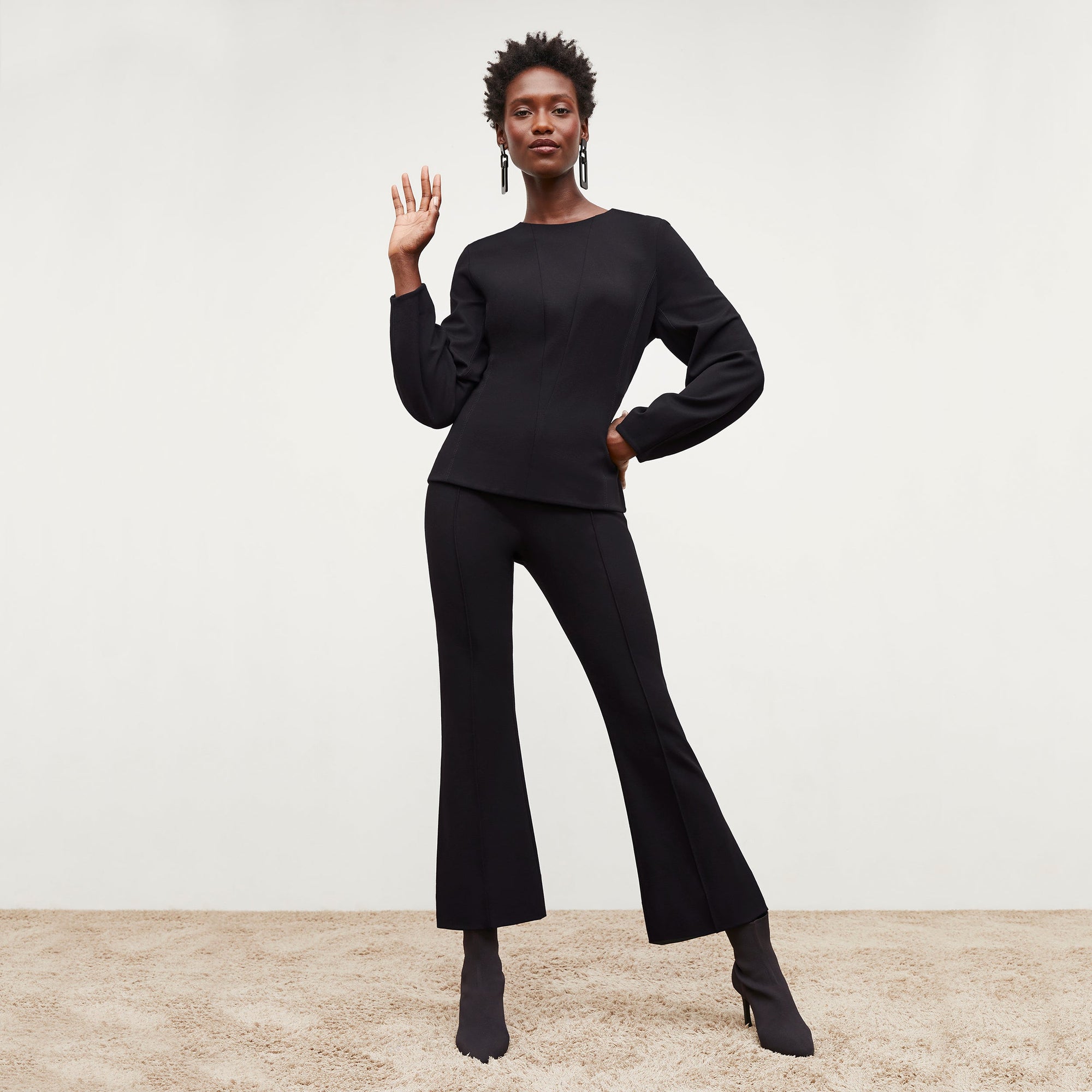 Front image of a woman standing wearing the rashida top in black 